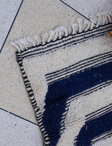 White and dark blue Moroccan rug with intricate Berber patterns enhancing a living room decor.