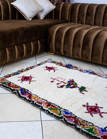 White Moroccan rug with vibrant Amazigh symbols enhancing a living room decor.